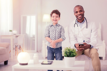 Joyful positive doctor and patient looking at you