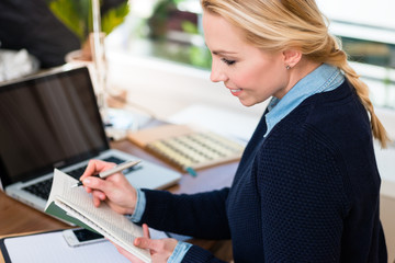 Close-up of a smiling woman writing in book