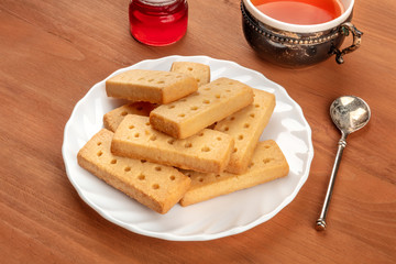 A photo of Scottish shortbreads, typical British butter cookies, on a rustic background with a vintage cup of tea, jam, and a place for text