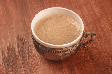A photo of coffee in a vintage cup, on a dark rustic wooden background with copy space, toned image