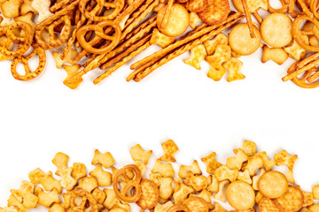 Many salt crackers, sticks, pretzels, and fishes, shot from aboveon a white background with a place for text. Party snacks mix, forming a frame with copy space - obrazy, fototapety, plakaty