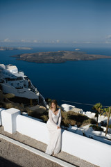 Bride in a wedding dress on the beach by the sea against the background of a blue sky.