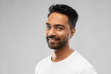 Obraz premium people concept - smiling young indian man over gray background