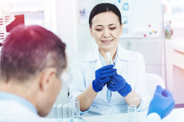 Cheerful nice woman holding a test tube