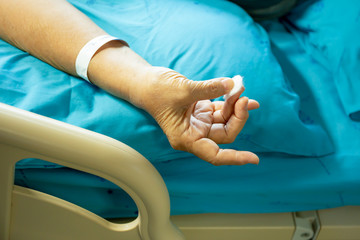 Senior patient using cotton wool stop blood bleeding from a finger.