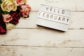 Hello February Word on Light box with roses flower bouquet on wooden background - obrazy, fototapety, plakaty