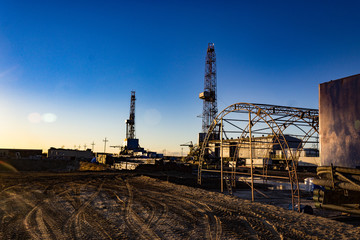 Fototapeta na wymiar construction of oil wells with two rigs in the morning sun