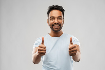 gesture and people concept - happy smiling young indian man in t-shirt showing thumbs up