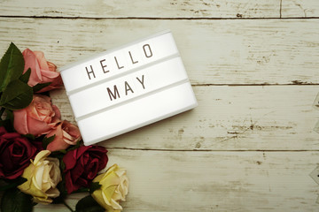 Hello May Word on Light box with roses flower bouquet on wooden background