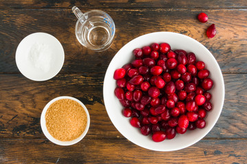 Ingredients for traditional cranberry sauce, berries, sugar, starch and water on wooden table, top view