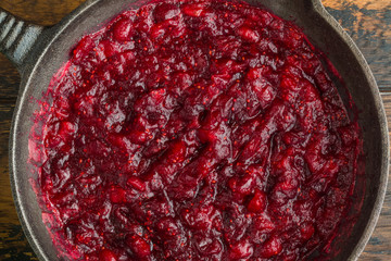 Traditional cranberry sauce in black cast-iron skillet, top view - 232058691