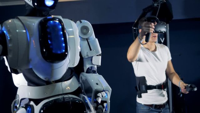 A guy is manipulating a robot with a virtual reality set. Virtual reality gaming concept.