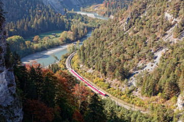 Train in sunny autumnal Ruinaulta - Rheinschlucht (Rhine canyon), Illanz/Glion - Reichenau, Switzerland