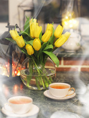 A bouquet of yellow tulips in a vase in the interior of a retro room. Retro interior with bouquet of tulips.