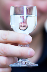 Man's upside down portrait reflection in Vodka glass shot