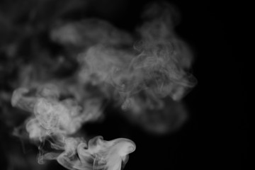 White smoke on a black background. Texture of smoke. Clubs of white smoke on a dark background for an overlay
