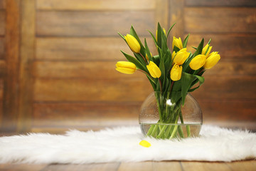 A bouquet of yellow tulips in a vase on the floor. A gift to a woman's day from yellow tulip flowers. Beautiful yellow flowers in a vase by wall.