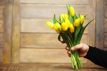 A bouquet of yellow tulips in a vase on the floor. A gift to a woman's day from yellow tulip flowers. Beautiful yellow flowers in a vase by wall.