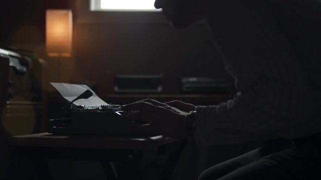 Hipster man sits down to type at his old vintage typewriter