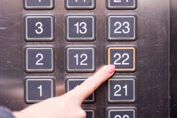 Fototapeta na wymiar Elevator buttons with finger pushing 22 floor