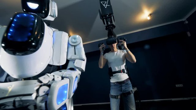 Young man is putting on virtual glasses and starts to navigate a robot with VR equipment