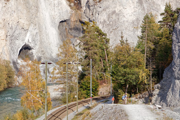 Tourists approaching Versam-Safien train station in sunny autumnal Ruinaulta - Rheinschlucht (Rhine canyon), Versam, Switzerland