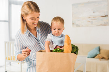cheerful happy mother showing groceries to son