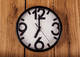 black clock with white dial on wooden background