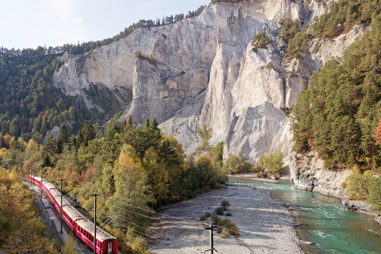 Passing by Glacier Express train in sunny autumnal Ruinaulta - Rheinschlucht (Rhine canyon) near Versam-Safien, Switzerland