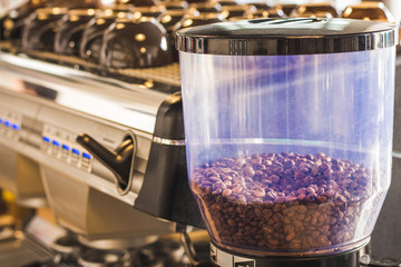 A coffee grinder container with some bean in it / Close up view of coffee bean in a container near cafe equipment