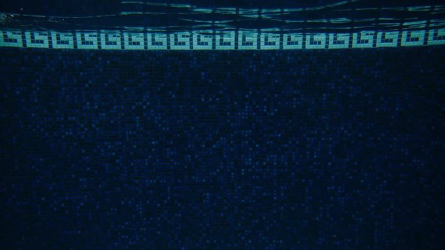 Cinematic shot of a heavily pregnant woman swimming backstroke