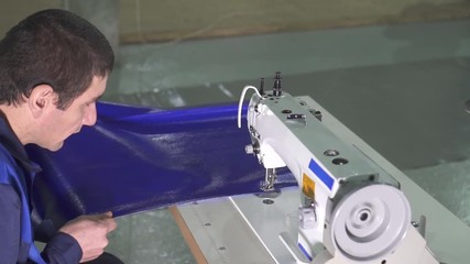 man worker at the sewing machine on the manufacture of awnings