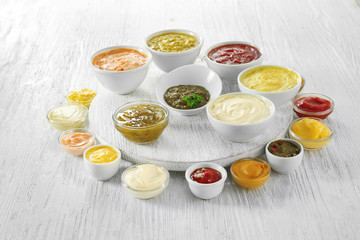 Different tasty sauces in bowls on white wooden table