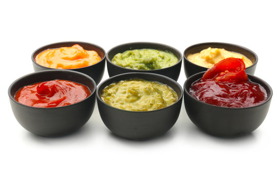 Different tasty sauces in bowls on white background