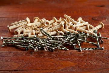 Dowels and screws closeup on a wooden background. Selective focus.