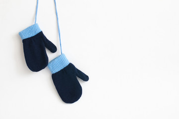 Blue knitted mittens hanging isolated on a white background.