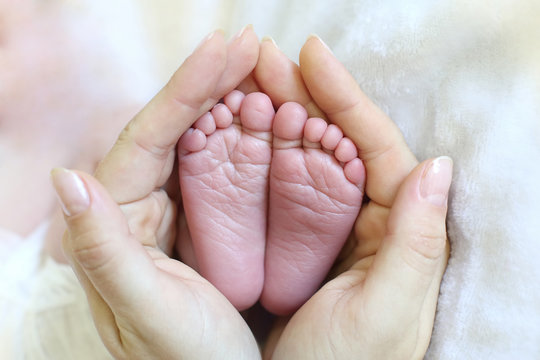 mom holds in her hands the feet of a newborn baby