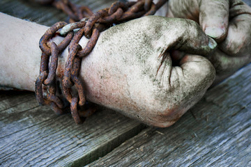 Powerful dirty male hands clenched into fists chained with rusty chain.
