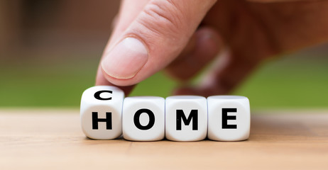 Hand is turning a dice and changes the word "come" to "home"