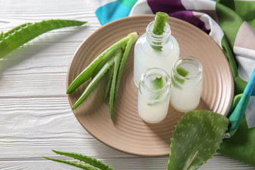 Bottles with fresh aloe vera juice on wooden table