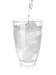 Pouring of water in glass with ice on white background