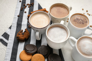 Many cups with tasty aromatic coffee and cookies on white table