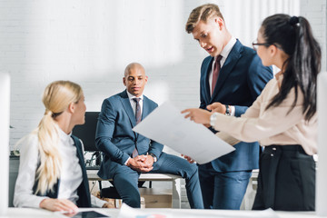 young multiethnic business people discussing paper in office