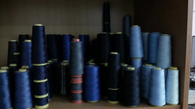 a lot of coils with blue threads. Bobbins are stacked in rows, one on the other.