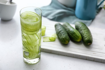Glass of fresh cucumber water on white table