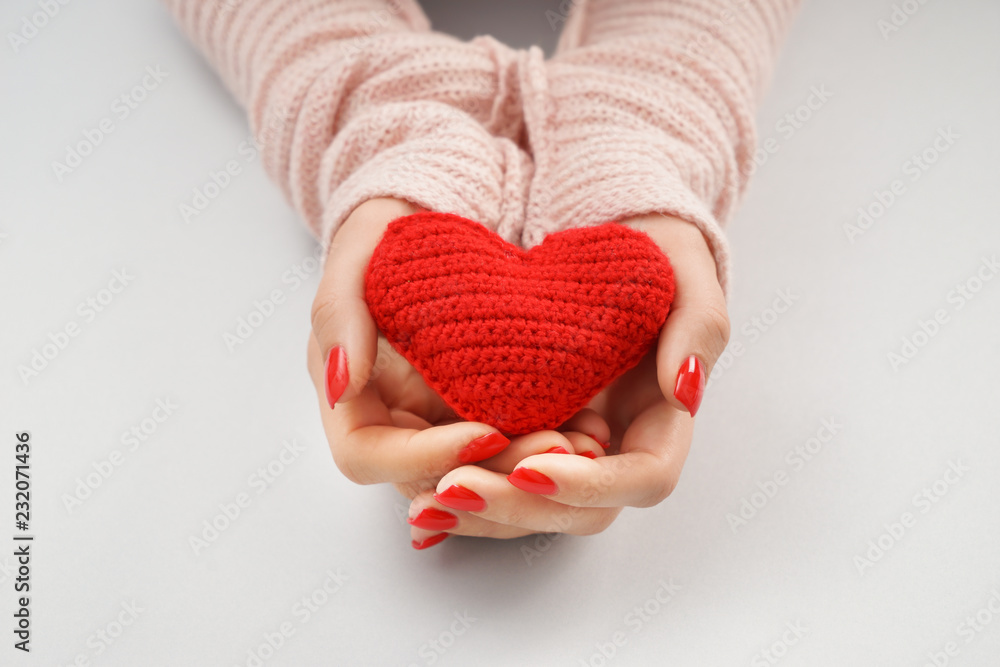 Wall mural woman holding knitted heart on white background, closeup