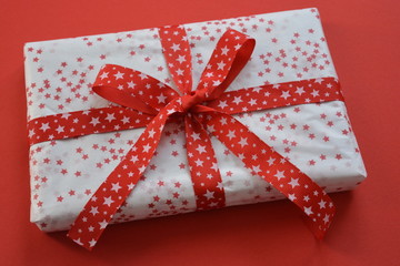 box with red ribbon and bow on red background