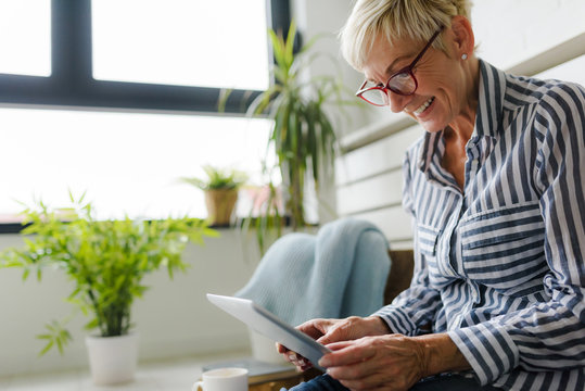 Smiling beautiful senior woman using digital tablet at home