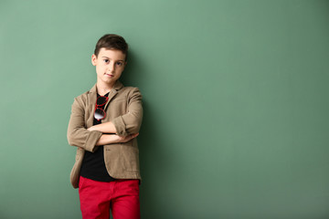 Cute boy in fashionable clothes on color background