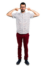 Handsome man with glasses covering both ears with hands